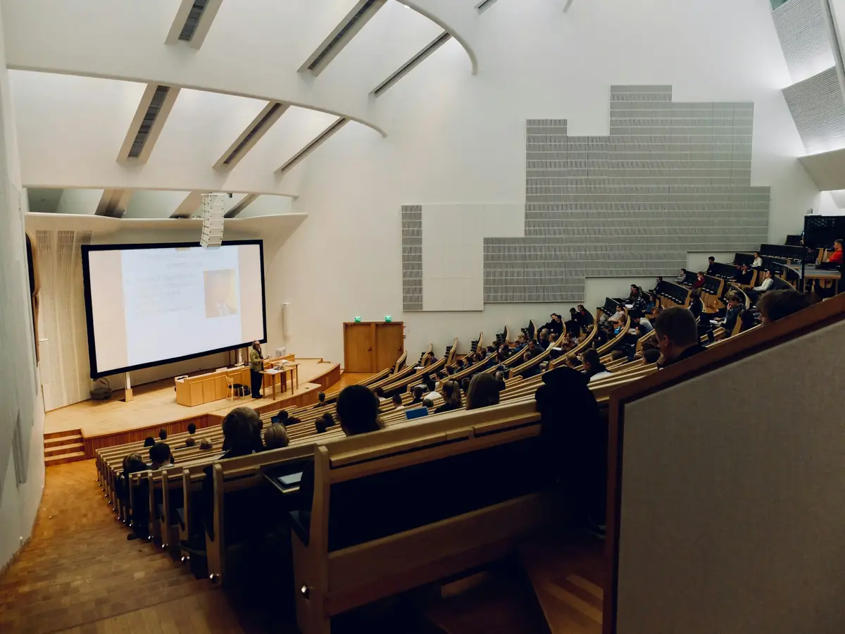 A tiered university lecture theatre with students facing a projection screen